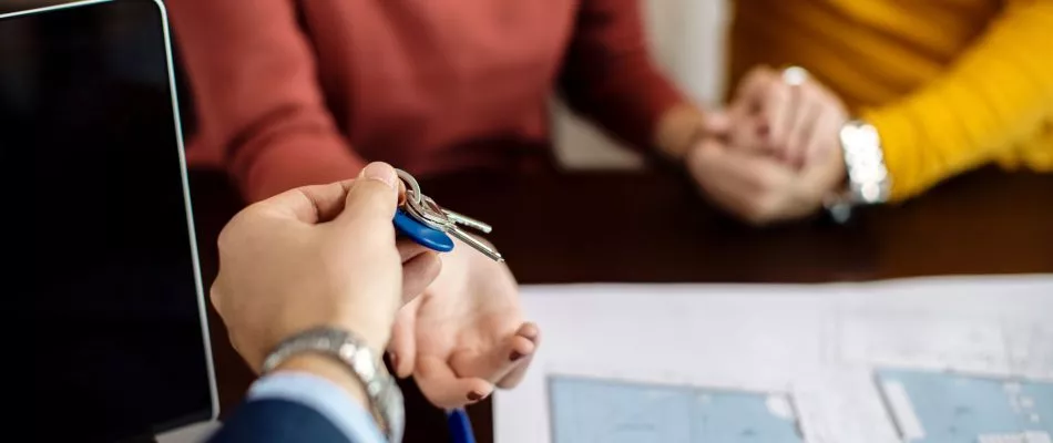 closeup-real-estate-agent-giving-couple-keys-their-new-home